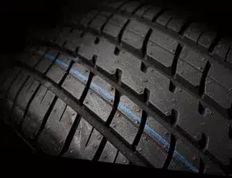 Close-up of a high-performance tire showcasing deep tread patterns and a blue center stripe, emphasizing grip and traction for enhanced road performance.