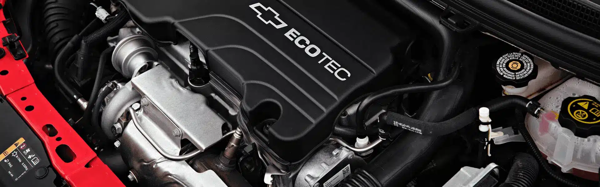 Close-up view of a Chevrolet Ecotec engine showcasing key components, including the aluminum intake manifold, turbocharger, and various hoses, highlighting its modern automotive engineering and design.