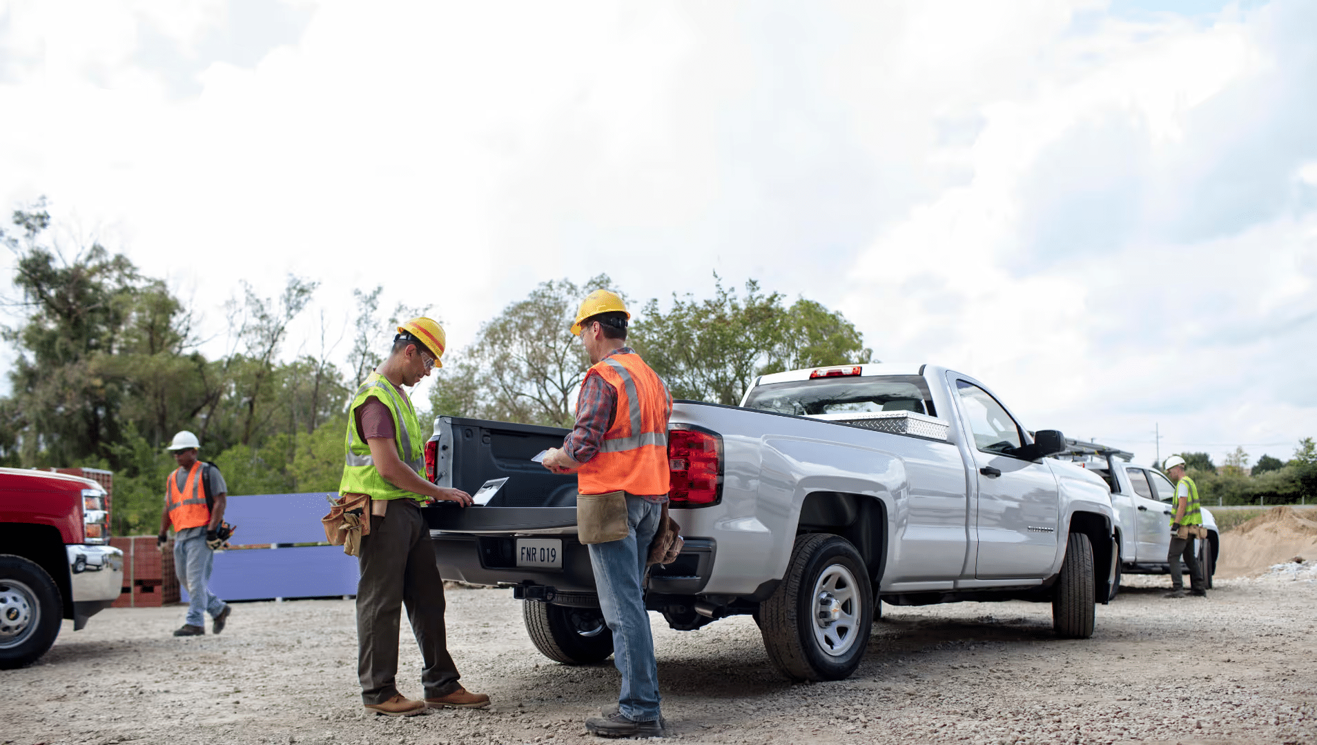 Chevrolet and GMC trucks displayed in front of a construction site, emphasizing strength and business capability, with a tagline highlighting a new look for business elite.