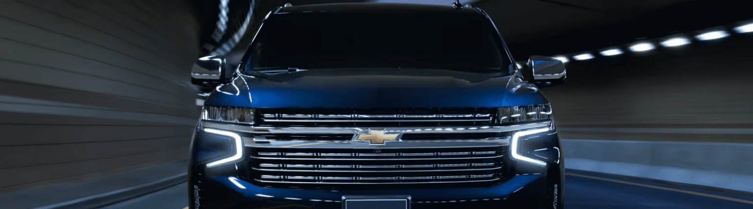 Front view of a sleek blue Chevrolet vehicle driving through a tunnel, showcasing its modern design and illuminated features.