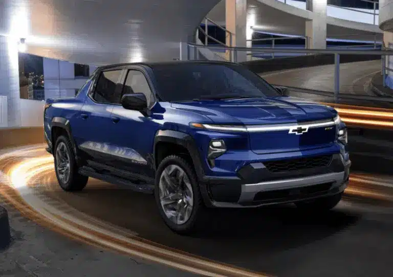Modern Chevy electric SUV parked in front of a contemporary building, showcasing sleek lines and innovative design. The vehicle stands out with its aerodynamic shape and stylish wheels, emphasizing its advanced technology and eco-friendly features.