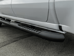Close-up view of a black running board installed on the side of a silver pickup truck, showcasing its textured surface and functional design.