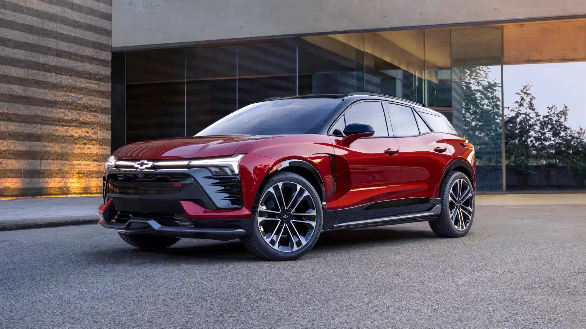 Sleek red Chevrolet SUV parked in an urban setting, showcasing its modern design and stylish features, with a reflective glass building in the background.