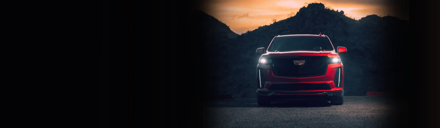 Red SUV parked on a scenic road with a mountainous backdrop during sunset, showcasing its sleek design and modern features. Ideal for appreciating luxury and performance in automotive photography.