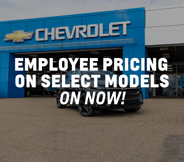 Black SUV parked in front of a Chevrolet dealership with blue facade.